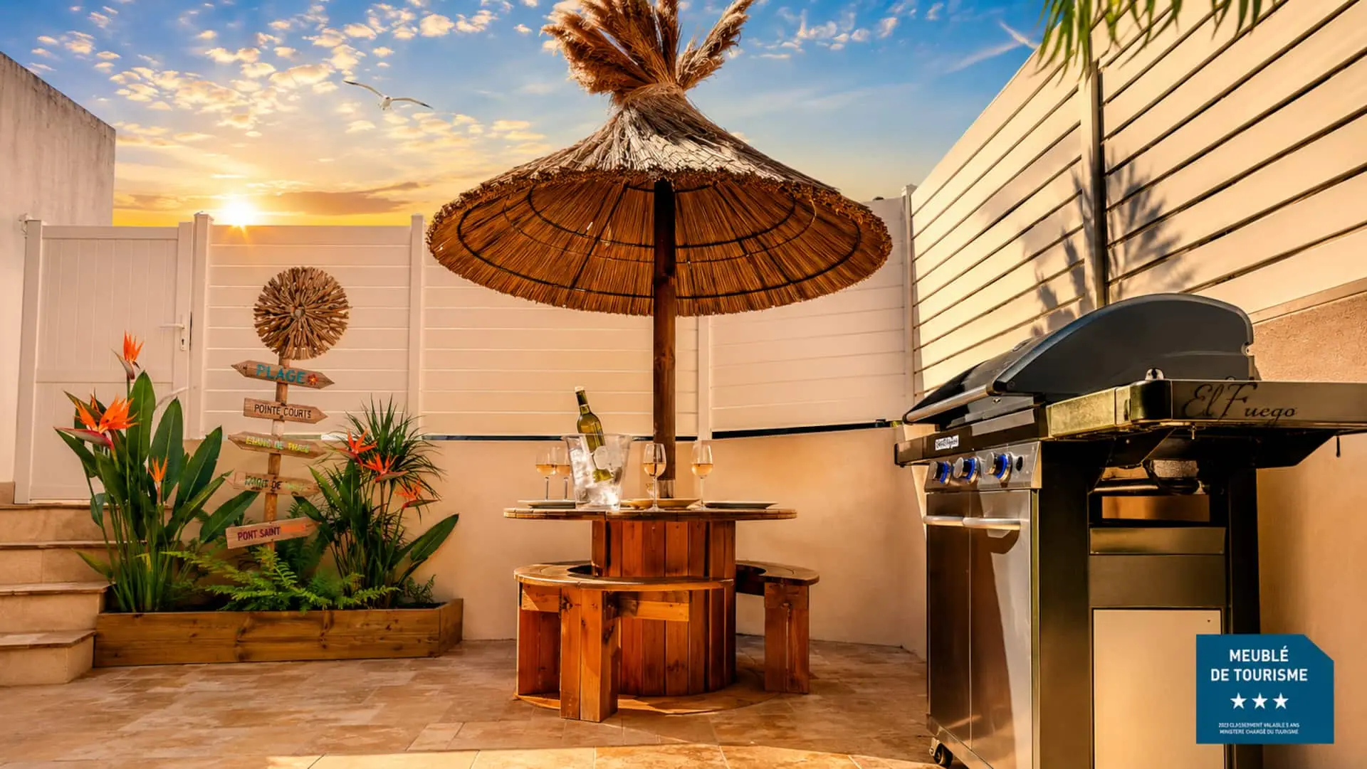 Jardin privé et terrasse de Sète Évasion aux Quilles avec paillote, table en bois et barbecue au coucher du soleil
