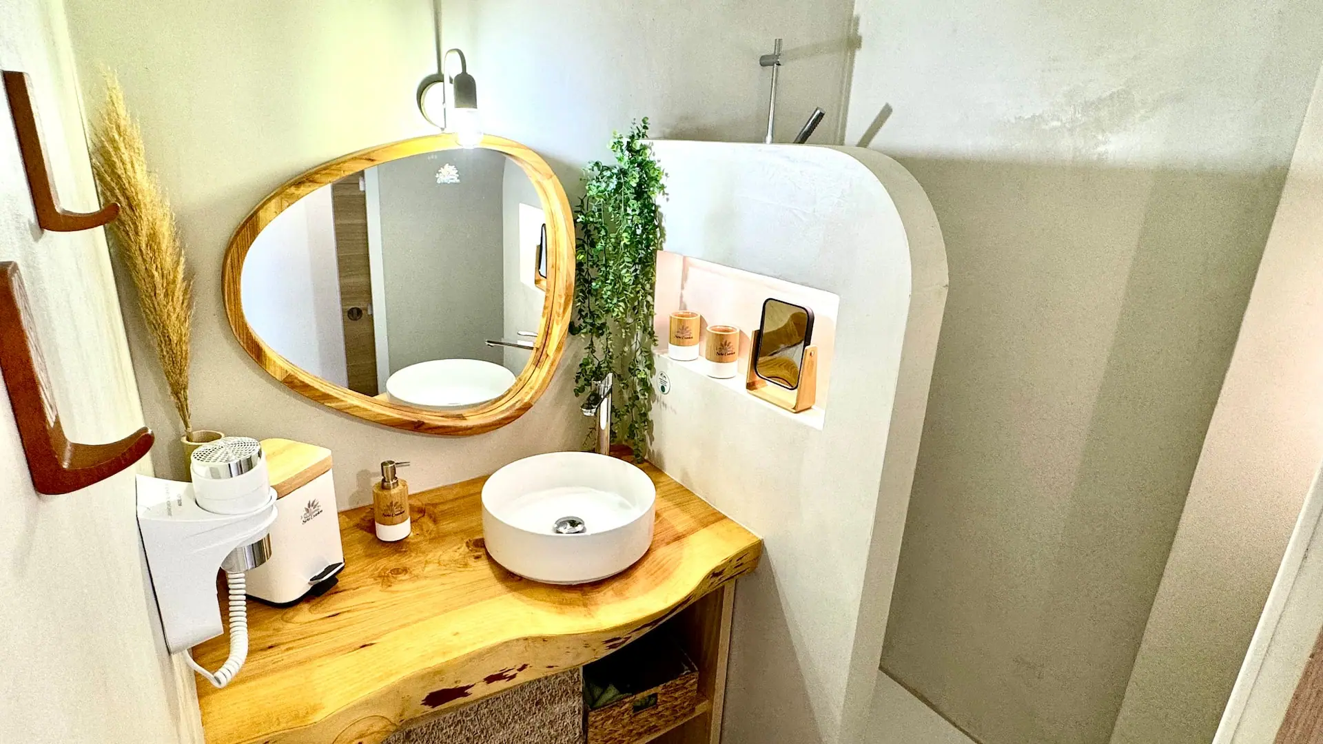 Salle d'eau avec vasque sur plan en bois, miroir ovale et douche à l'italienne